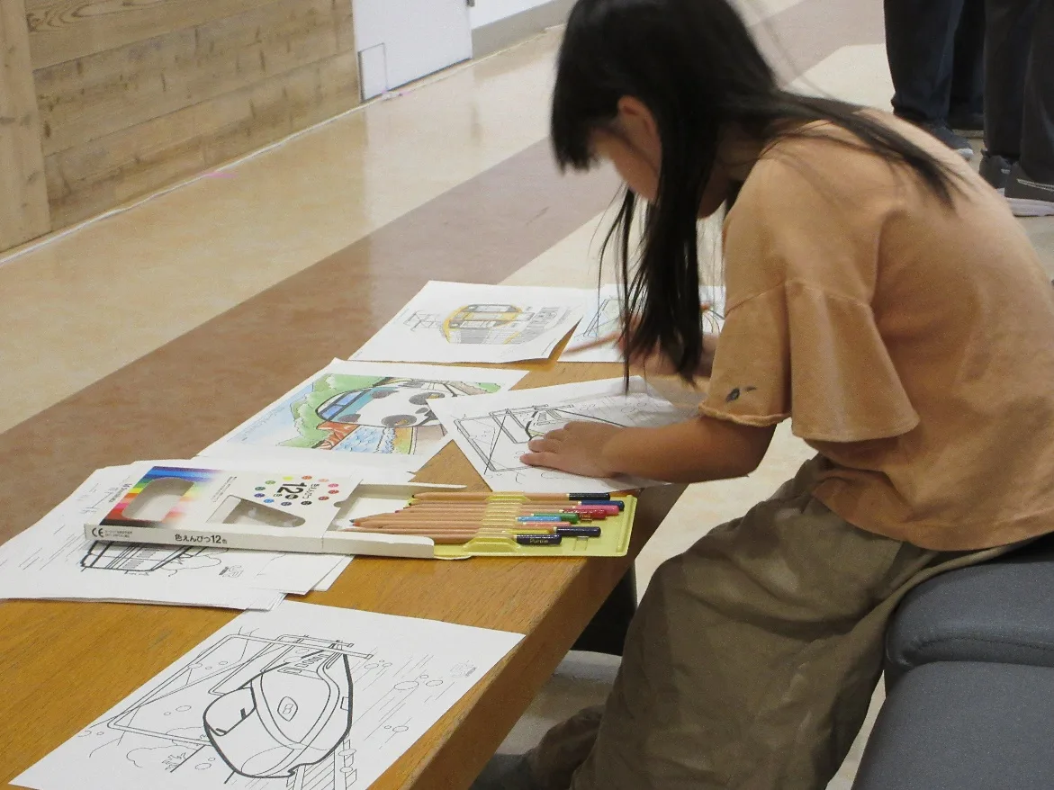 新幹線の下絵に色をぬる子ども