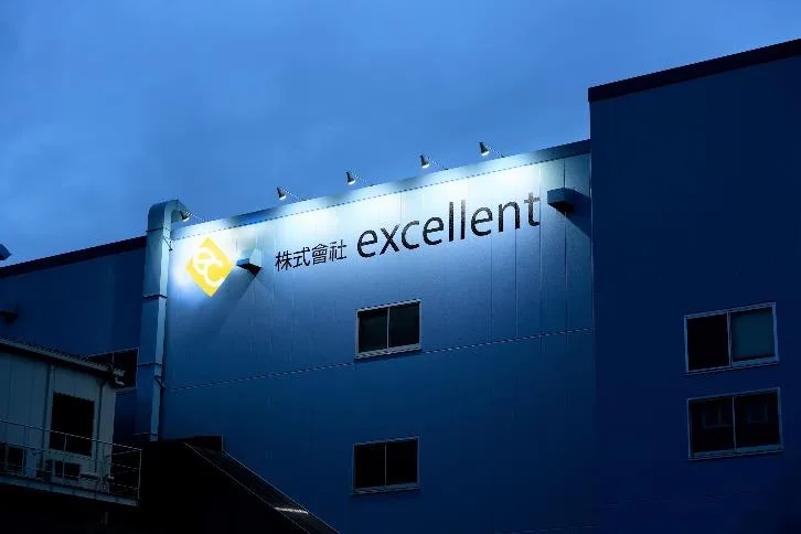 夕暮れにロゴが灯る株式會社 excellent の社屋